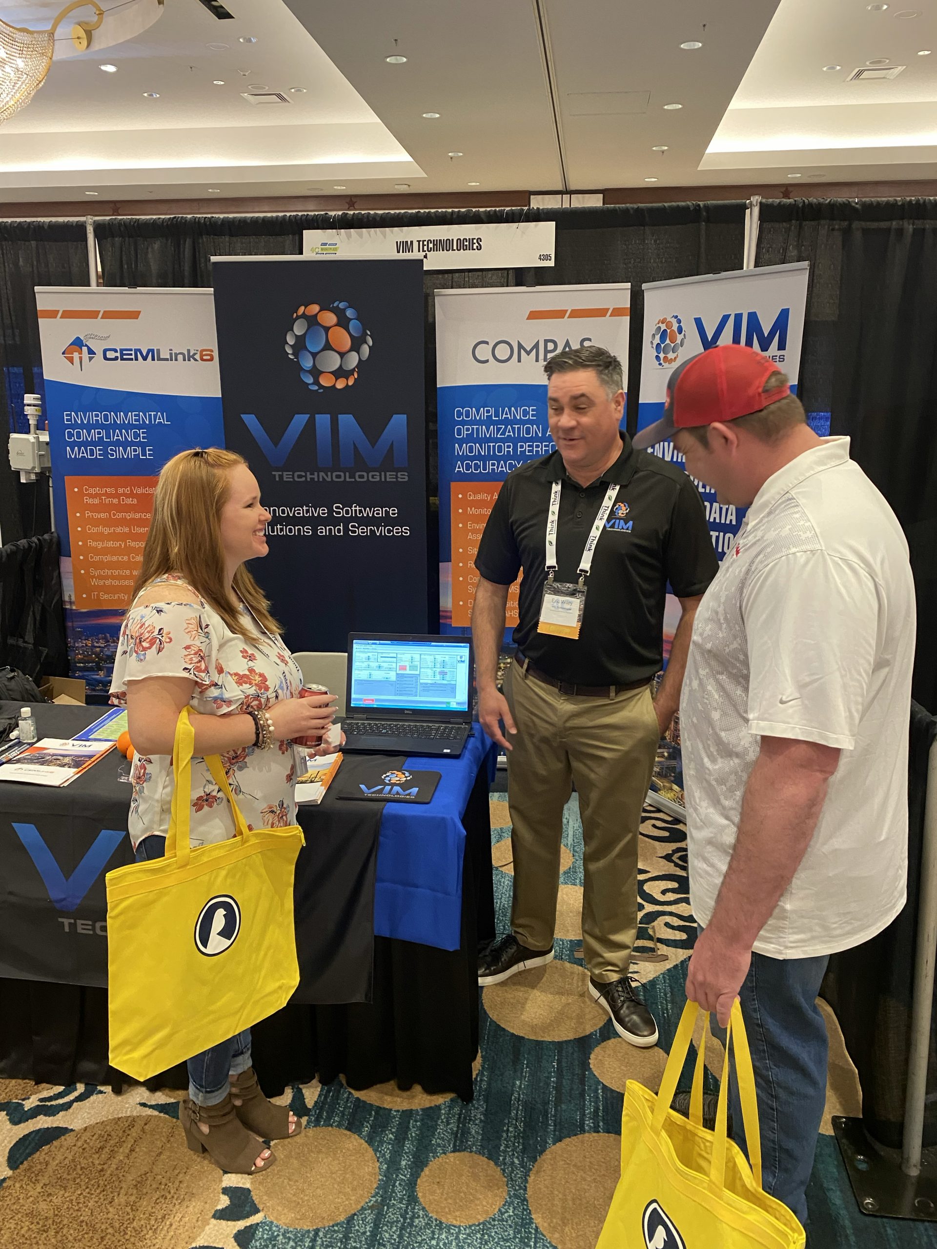 Conference Attendees visiting VIM Technologies exhibit and discussing with representative. 